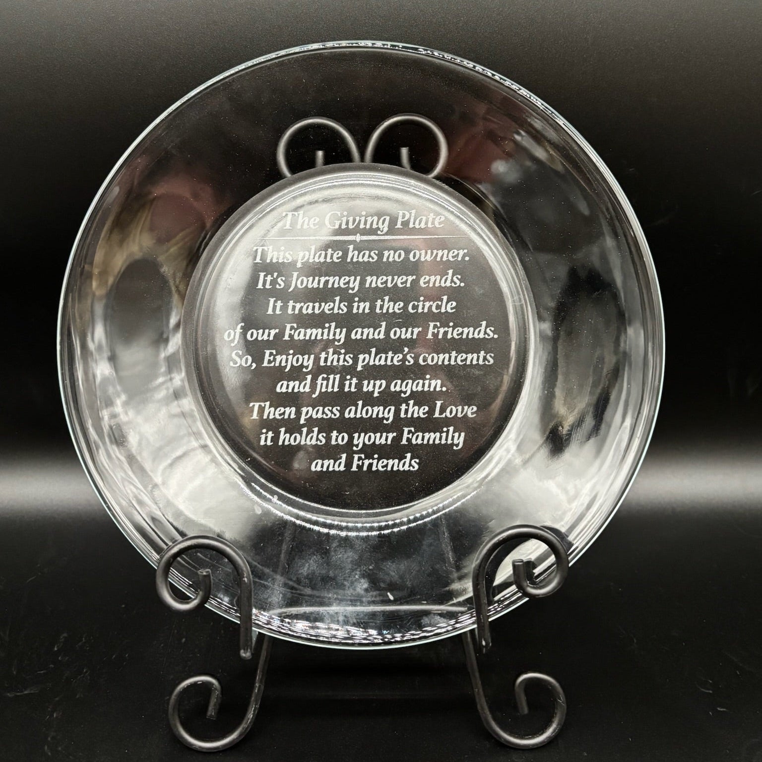 Clear glass plate with engraved text on a dark background